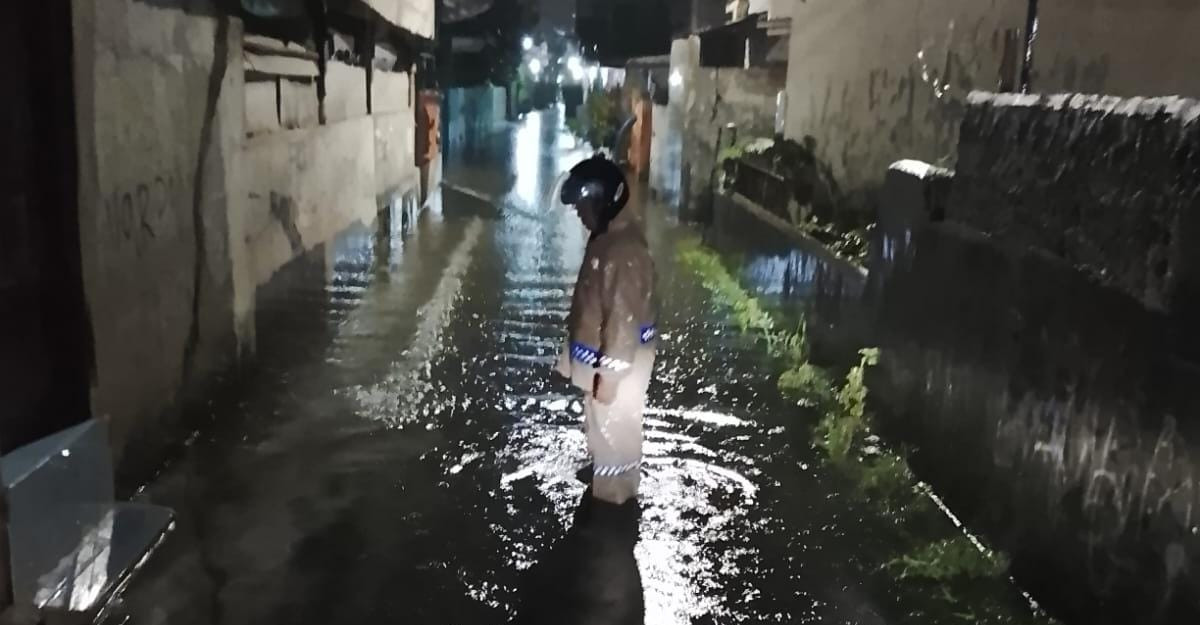 Antisipasi Dampak Hujan, Bhabinkamtibmas Kalibaru Pantau Genangan Air di Jalan Rawa Bakti